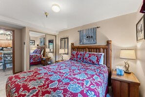 Ein Schlafzimmer mit einem großen Bett, einem Holz-Kopfteil, einem Nachttisch mit Lampe und einem Spiegel an der Wand.