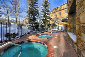 Un área de piscina con tres jacuzzis, rodeada por un muro de piedra y un sendero de ladrillo.