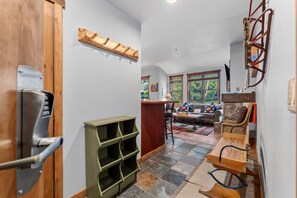 Ein Flur mit einer Holztür, einem grünen Regalschrank, einem Steinkamin und einer Sitzecke mit Sofa und Tisch.