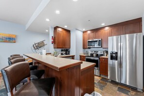 Eine moderne Küche mit Holzschränken, Edelstahlgeräten und einer Bar mit Sitzgelegenheiten.