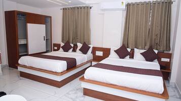 A hotel room with two beds, a wardrobe, and an air conditioning unit.
