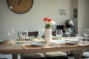 A dining table set with plates, glasses, and a vase of flowers.
