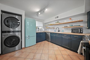 Une cuisine équipée d’un lave-linge, d’un réfrigérateur, d’un four à micro-ondes et d’un évier.