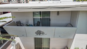 Un balcon orné d’un motif décoratif représentant un buffle, une porte-fenêtre coulissante et deux chaises.