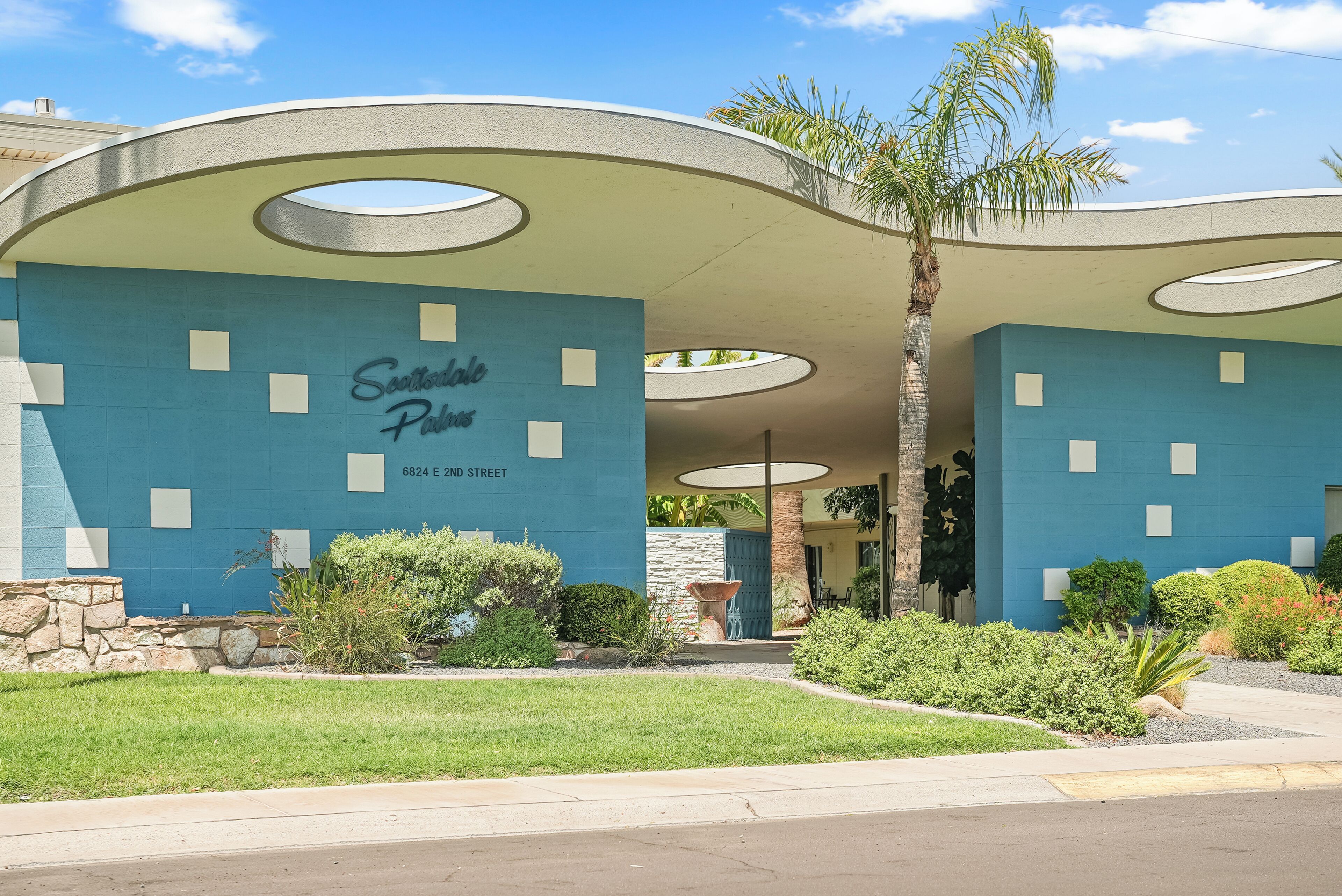 Um edifício com fachada azul, uma placa com a inscrição 'Scottsdale Plaza' e o endereço '6824 E 2nd Street'.