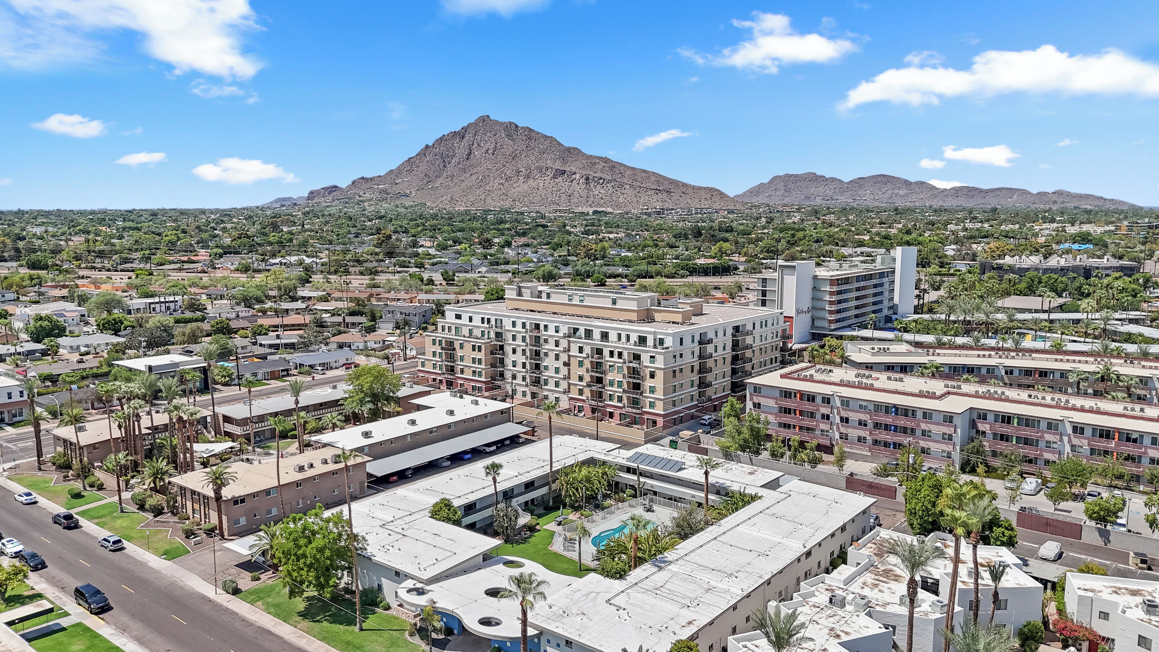 Um hotel com vários andares, um pátio central e uma montanha ao fundo.