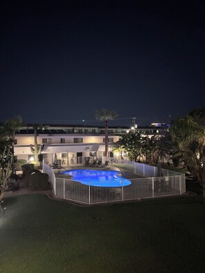 A swimming pool surrounded by a white fence, with a building in the background.