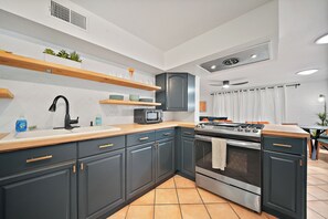 Una cocina moderna con armarios oscuros, una estufa de acero inoxidable y un microondas.