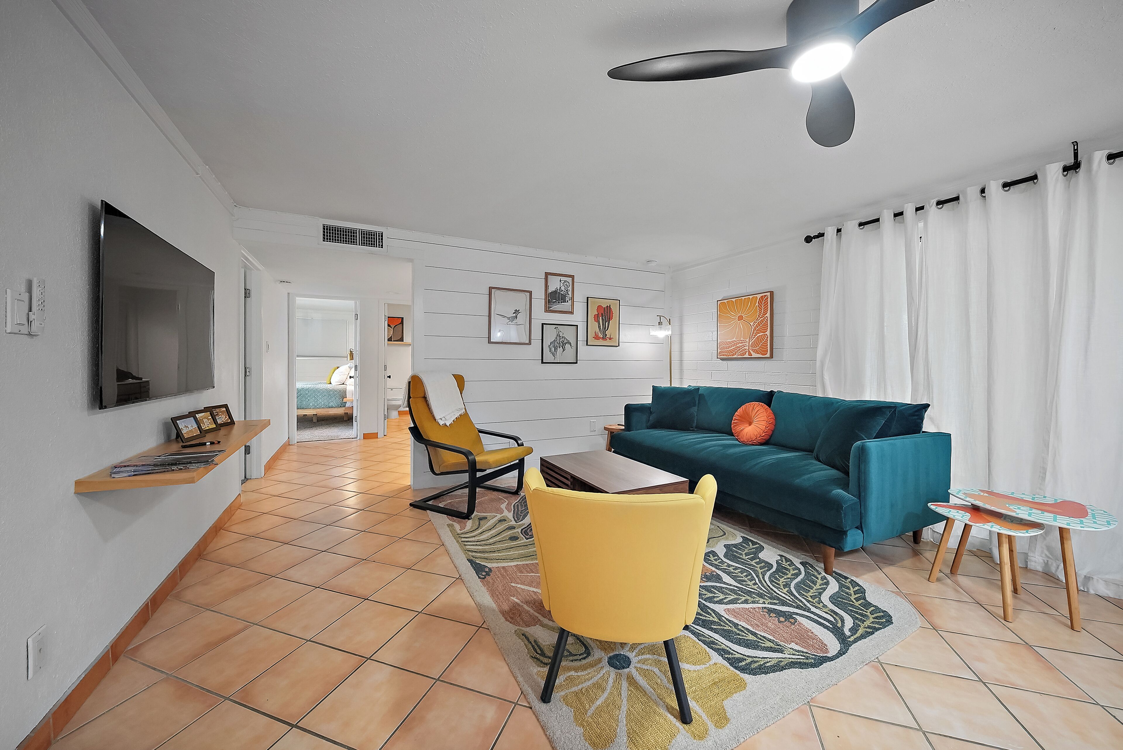 Uma sala de estar moderna com um sofá, cadeiras, uma mesa de centro e uma televisão fixada na parede.
