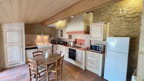 A kitchen with wooden cabinets, a gas stove, a sink, and a refrigerator.