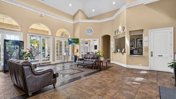 A spacious lobby with a leather sofa, a flat-screen TV, and a reception desk.