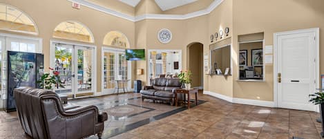 A spacious lobby with a leather sofa, a flat-screen TV, and a reception desk.