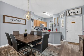 Eine moderne Küche mit Essbereich, ausgestattet mit einer Chandelier, Holzschränken und einem Schild mit der Aufschrift 'Küche'.