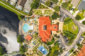 Eine Vogelperspektive zeigt ein Resort mit mehreren Schwimmbecken, einem großen Hauptgebäude und einem Parkplatz.