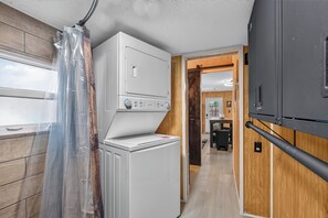 A compact laundry room with a washing machine, dryer, and a small table with a chair. - Brand new Cozy 1-bedroom building in charming Lake Placid with AC (Lake Placid)