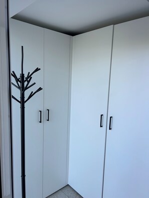 A corner of a room with white wardrobes and a black coat stand.