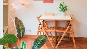 A dining area with a wooden table and chairs, a potted plant, and a wall with four framed pictures. - Entire Westminster Townhouse Near WestminsterAbbey (London)