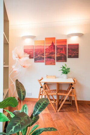 A dining area with a wooden table and chairs, a potted plant, and a wall with four framed pictures. - Entire Westminster Townhouse Near WestminsterAbbey (London)