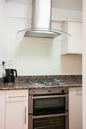 Eine Küche mit Gasherd, Backofen und Kaffeemaschine auf der Arbeitsfläche.