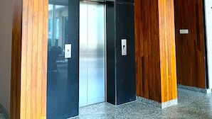 An elevator in a building with a modern design, featuring wooden accents and a granite floor.