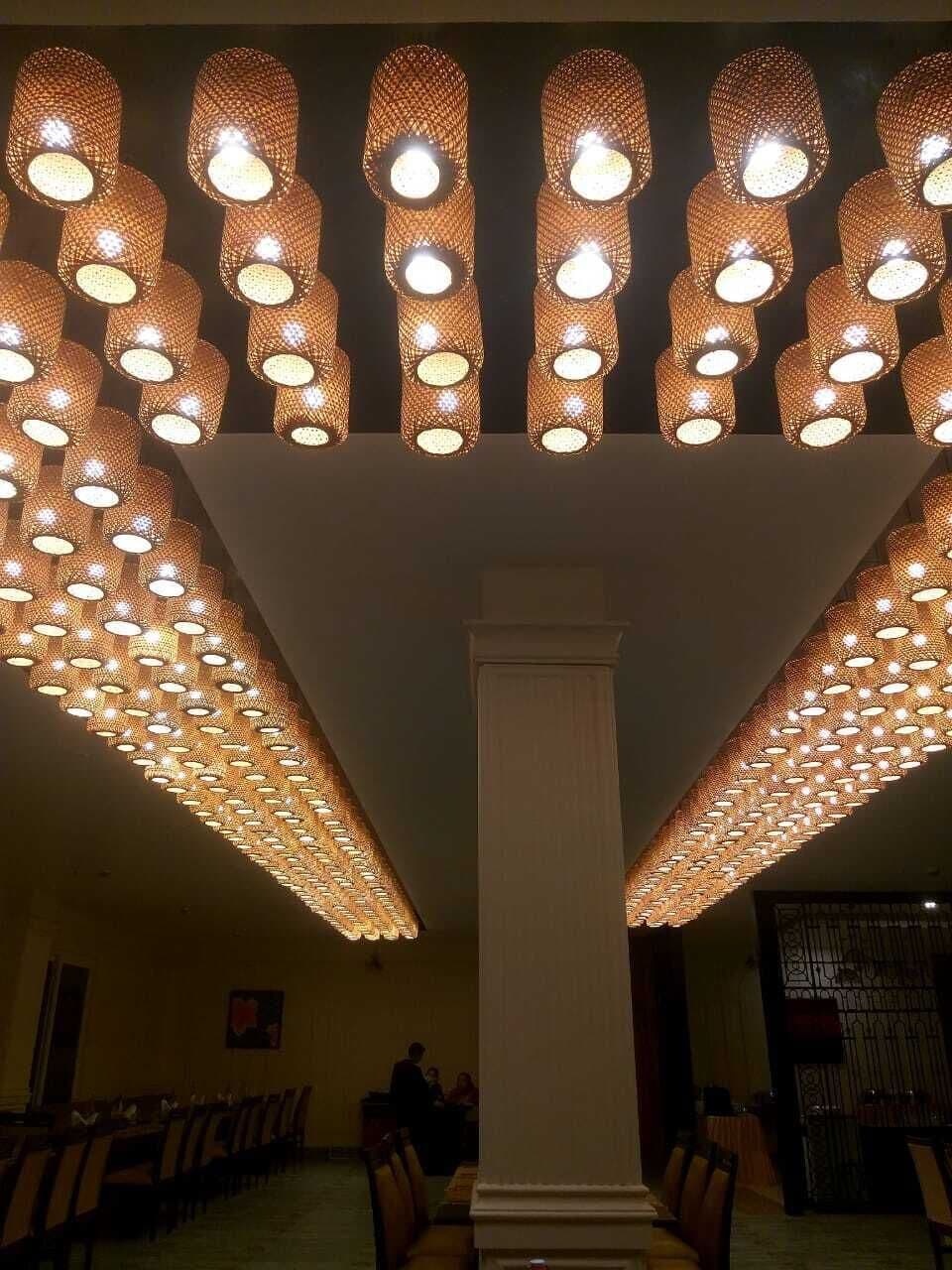 Une pièce dotée d’une grande colonne centrale, de plusieurs rangées de tables et d’un luminaire décoratif au plafond.