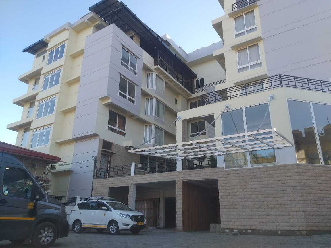 Un edificio residencial de varios pisos con techo plano, balcones y zona de estacionamiento techada.