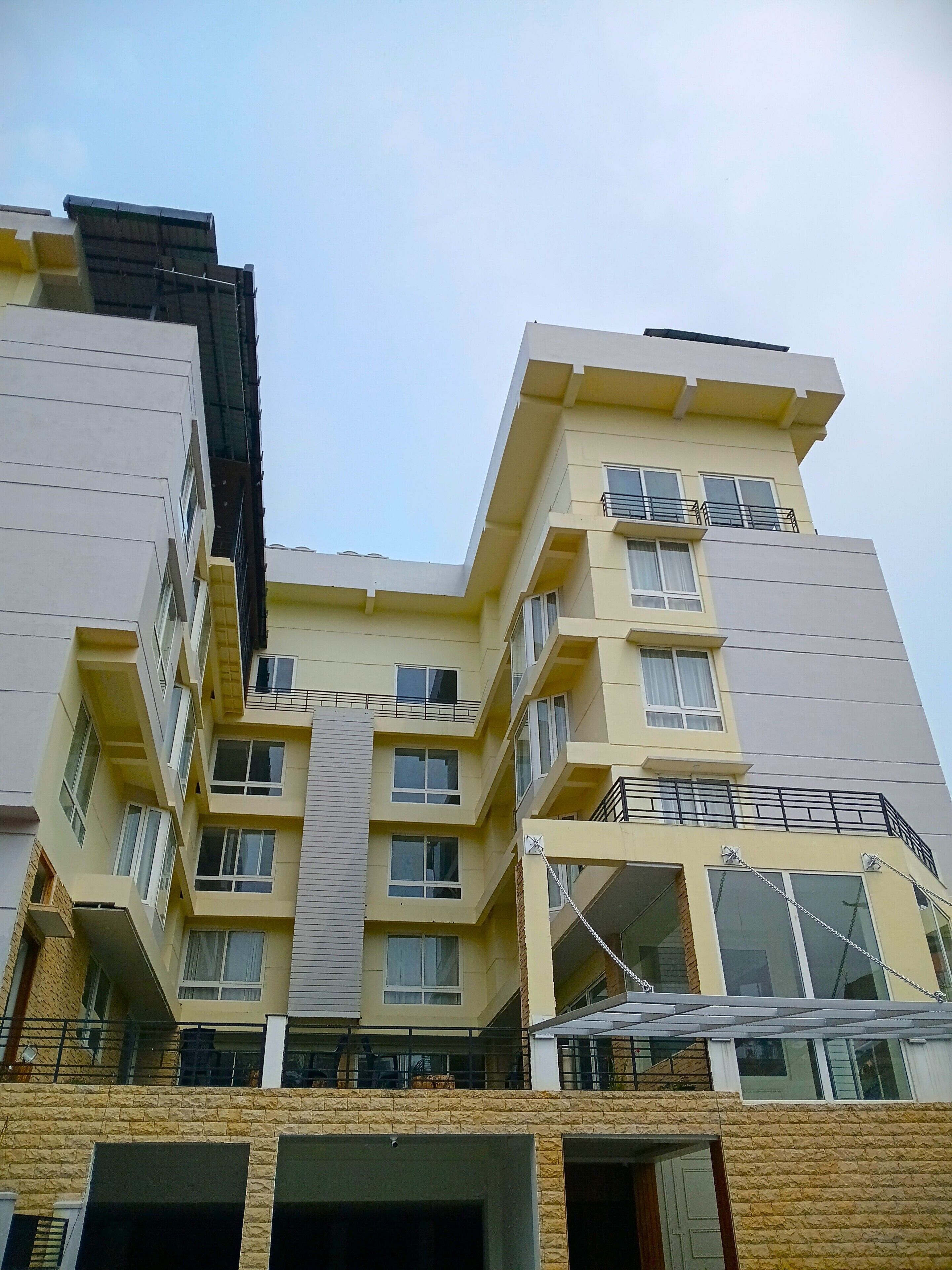 A multi-story residential building with balconies, large windows, and a flat roof.