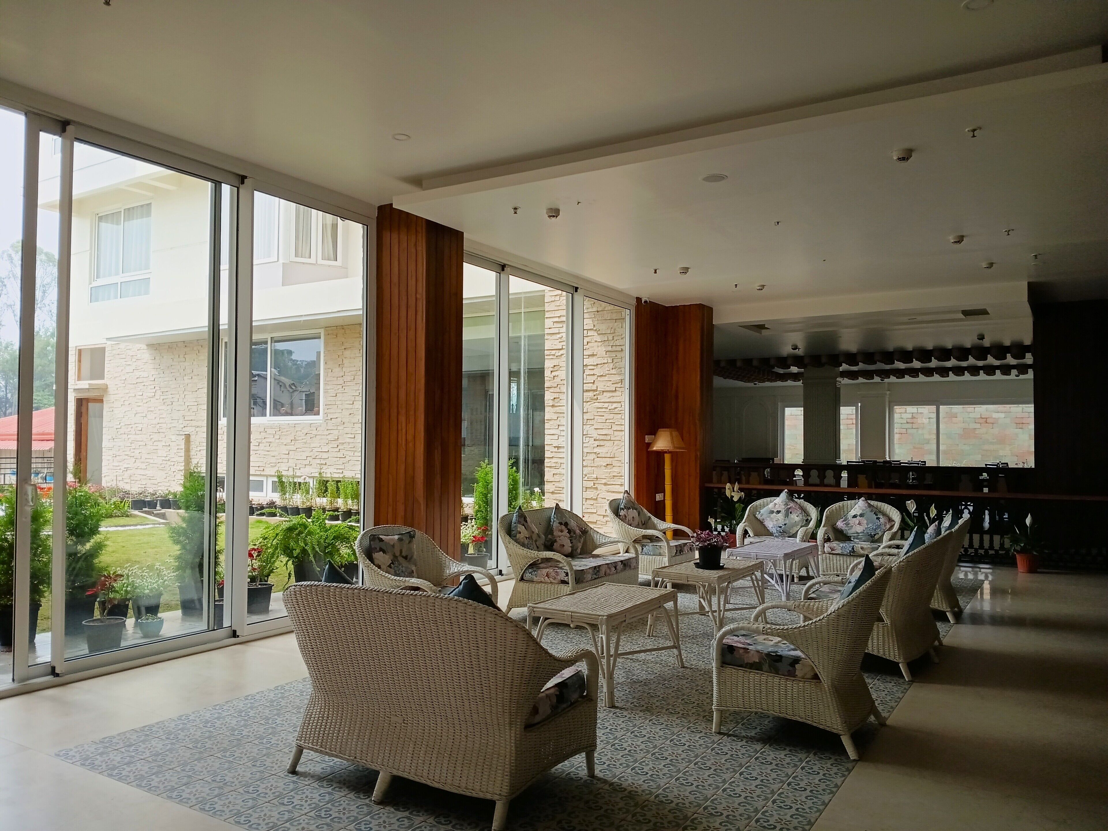 A spacious indoor area with wicker furniture, large windows, and a view of a building outside.