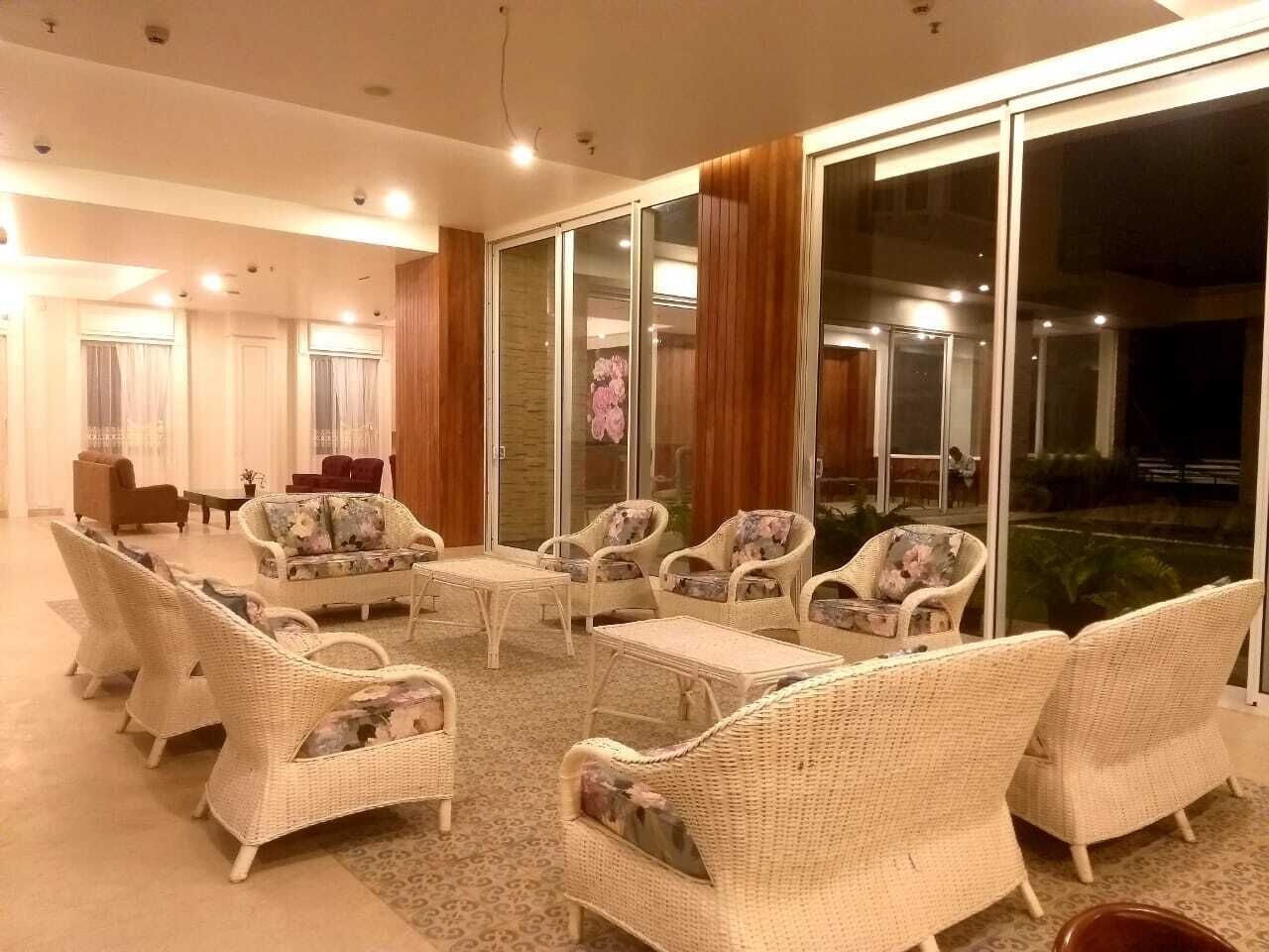 Un espace intérieur spacieux, aménagé avec des meubles en osier, doté d’une cloison en verre et offrant une vue sur l’extérieur.