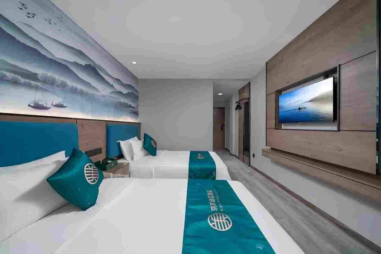 Habitación de hotel con dos camas, un mural grande en la pared, un televisor y vista al mar.