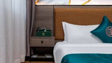 A hotel room with a bed, a nightstand, a green box, and a pillow with a globe design.