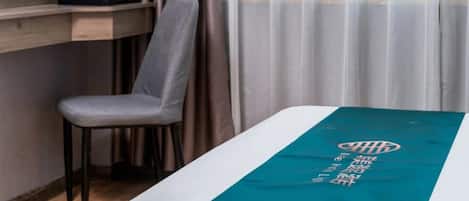 Habitación de hotel con cama, una silla, cafetera y ventana con cortinas.