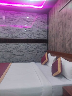A hotel room with a bed, pillows, a wooden headboard, and a marble-patterned wall.