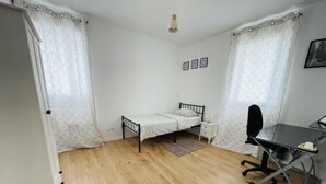 Une petite chambre à coucher, bien rangée, avec un lit simple, un bureau et une chaise.