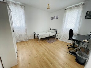 A small, tidy bedroom with a single bed, a desk, and a chair.