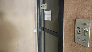Une porte dotée d’un panneau en verre, un interphone fixé au mur et un panneau indiquant une zone de protection des eaux spécifique au site.