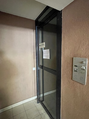 A door with a glass panel, a wall-mounted intercom, and a sign indicating a site-specific water protection area.