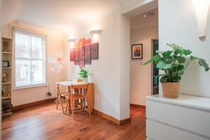 Ein Zimmer mit Esstisch, Stühlen, einer Zimmerpflanze und Bildern an der Wand.