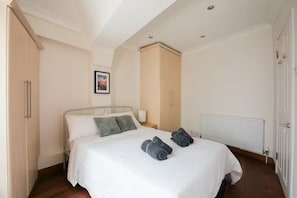 A bedroom with a bed, a wardrobe, a radiator, and a door. - Two Bedrooms Flat Near Big Ben & Westminster Abbey (London)