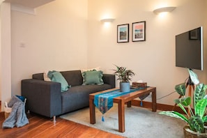 A living room with a sofa, a coffee table, a TV, and two framed pictures on the wall. - Two Bedrooms Flat Near Big Ben & Westminster Abbey (London)