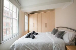 Ein Schlafzimmer mit Bett, Kissen, einem Fenster und einem Kleiderschrank.