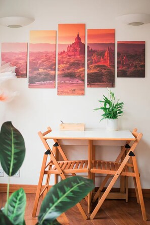 Ein Essbereich mit Holztisch und Stühlen, einem Blumentopf und einer Wand mit vier gerahmten Bildern.