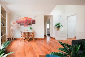 A spacious living area with a wooden floor, a dining table with chairs, a white cabinet, and a potted plant. - Two Bedrooms Flat Near Big Ben & Westminster Abbey (London)