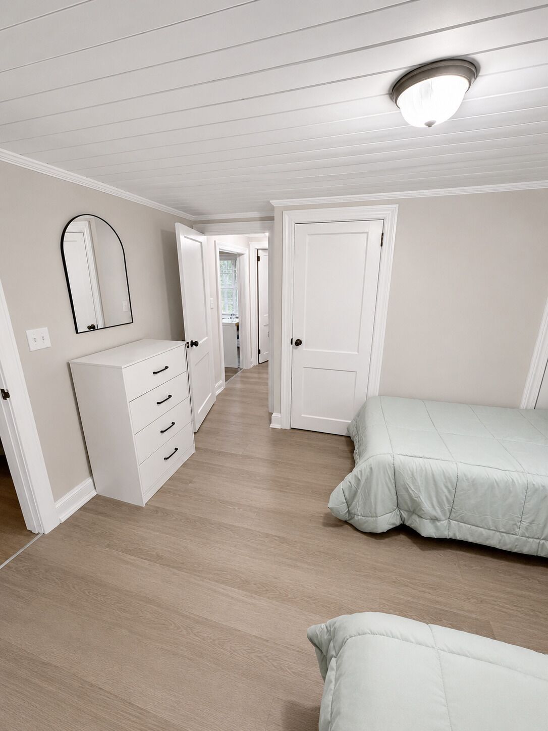 Ein Schlafzimmer mit einem Bett, einem Schminktisch, einem Spiegel und einer Tür.