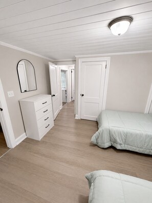 Ein Schlafzimmer mit einem Bett, einem Schminktisch, einem Spiegel und einer Tür.