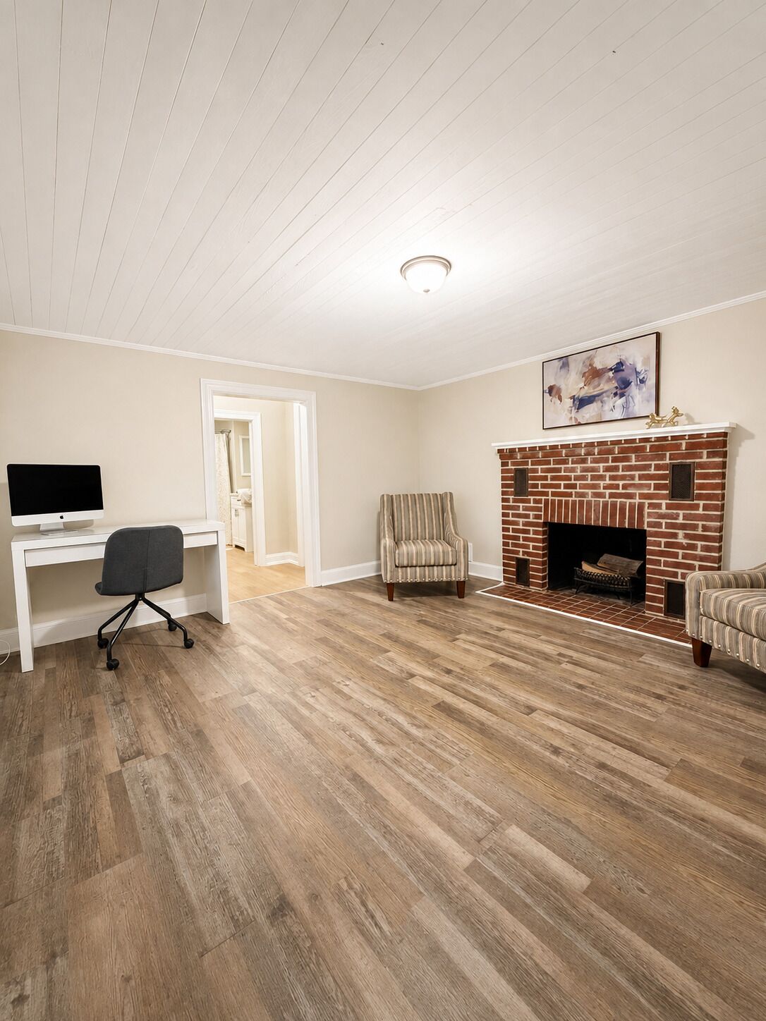 A room with a fireplace, a desk with a computer, and a chair.