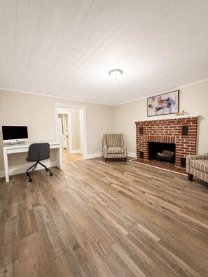A room with a fireplace, a desk with a computer, and a chair. - The Stone House • 5 Min to JMU • Fenced Yard • Peaceful Retreat No Neighbors (Harrisonburg)