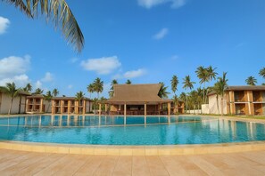 Ein Resort mit großem Schwimmbad, mehreren Gebäuden mit Veranden und Palmen.