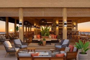 Ein großzügiger Außenbereich mit Loungemöbeln, darunter Sofas und Sessel, sowie eine Bar.