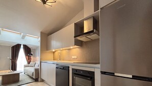 A modern kitchen with built-in appliances, a dining area with a sofa, and a view of the living room. - Penthouse Suite with Private Terrace (Istanbul)